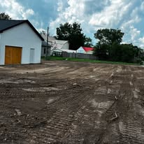 Large graded dirt lot next to a white garage